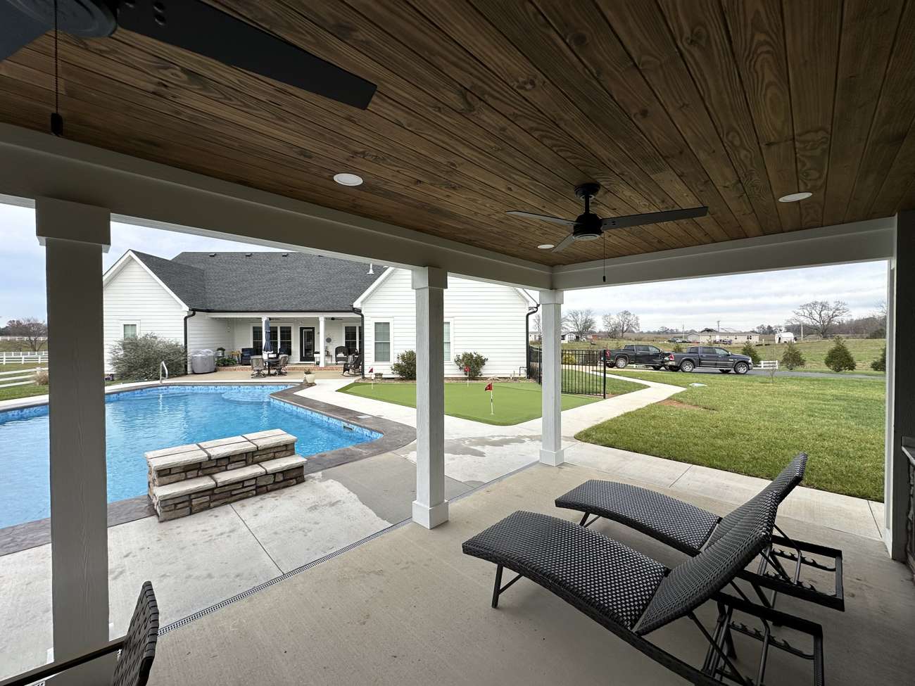 Covered patio with a wood ceiling looking out over a pool